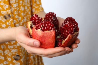 Photo of Woman holding fresh pomegranate on light background, closeup