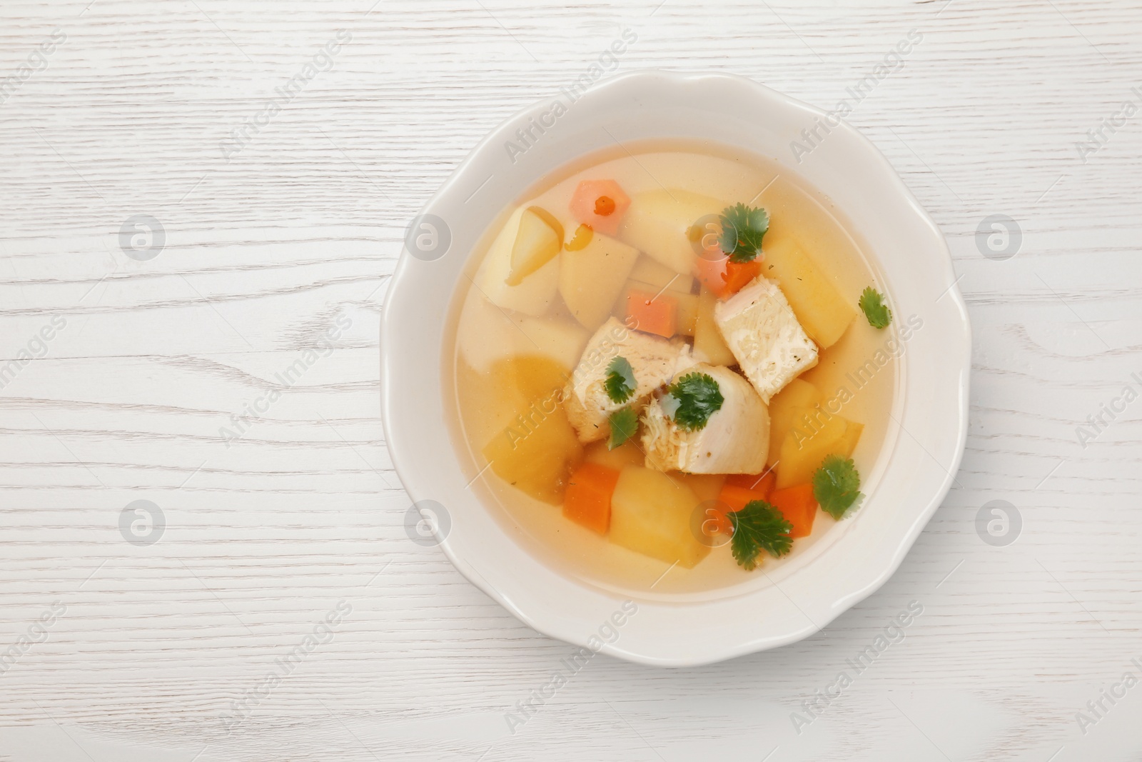 Photo of Homemade chicken soup in dish on wooden background, top view with space for text