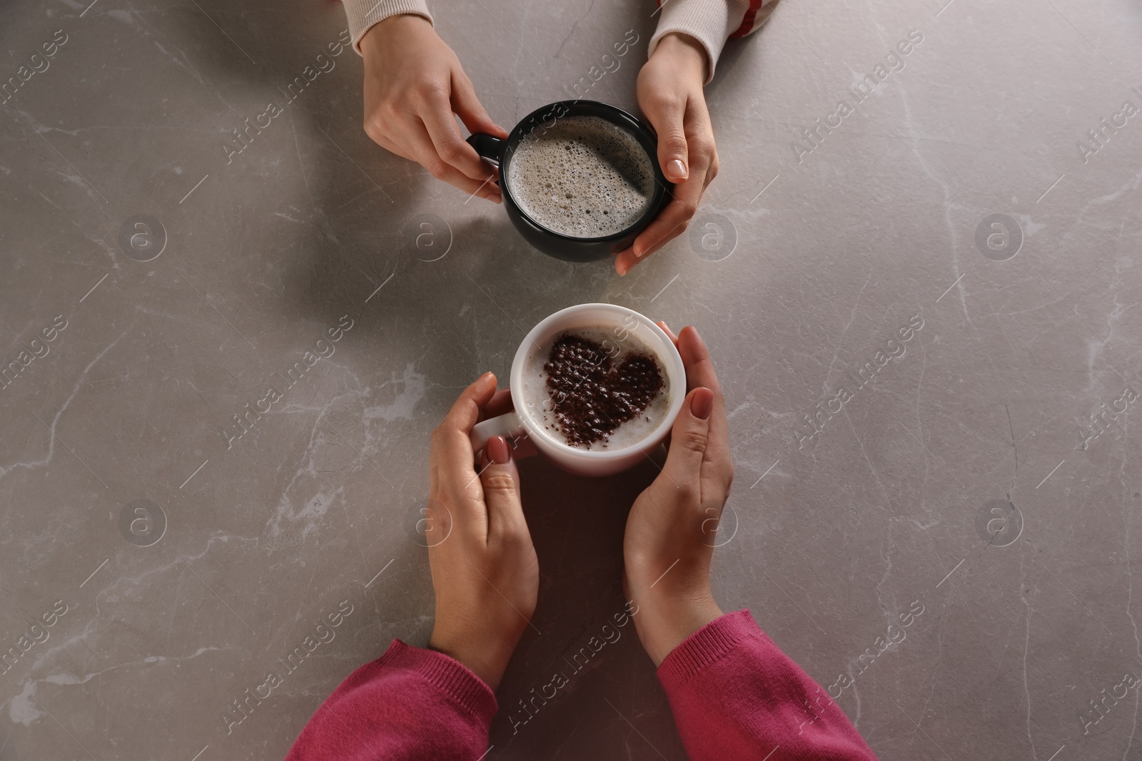 Photo of Women with cups of hot coffee at grey table, above view