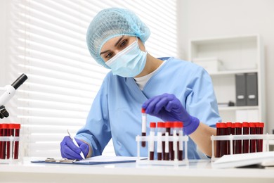 Laboratory testing. Doctor with blood samples in tubes at white table indoors