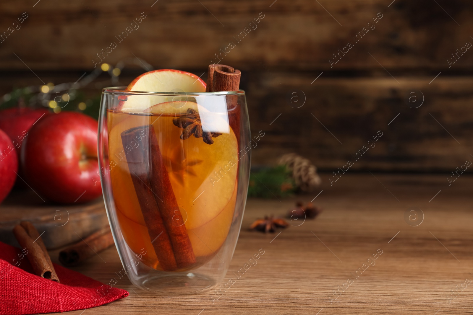 Photo of Hot mulled cider on wooden table, space for text