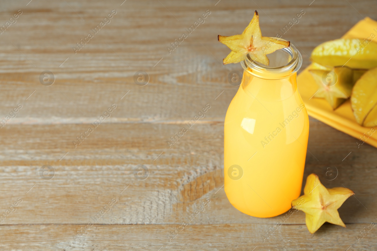 Photo of Delicious carambola juice and fresh fruits on wooden table. Space for text