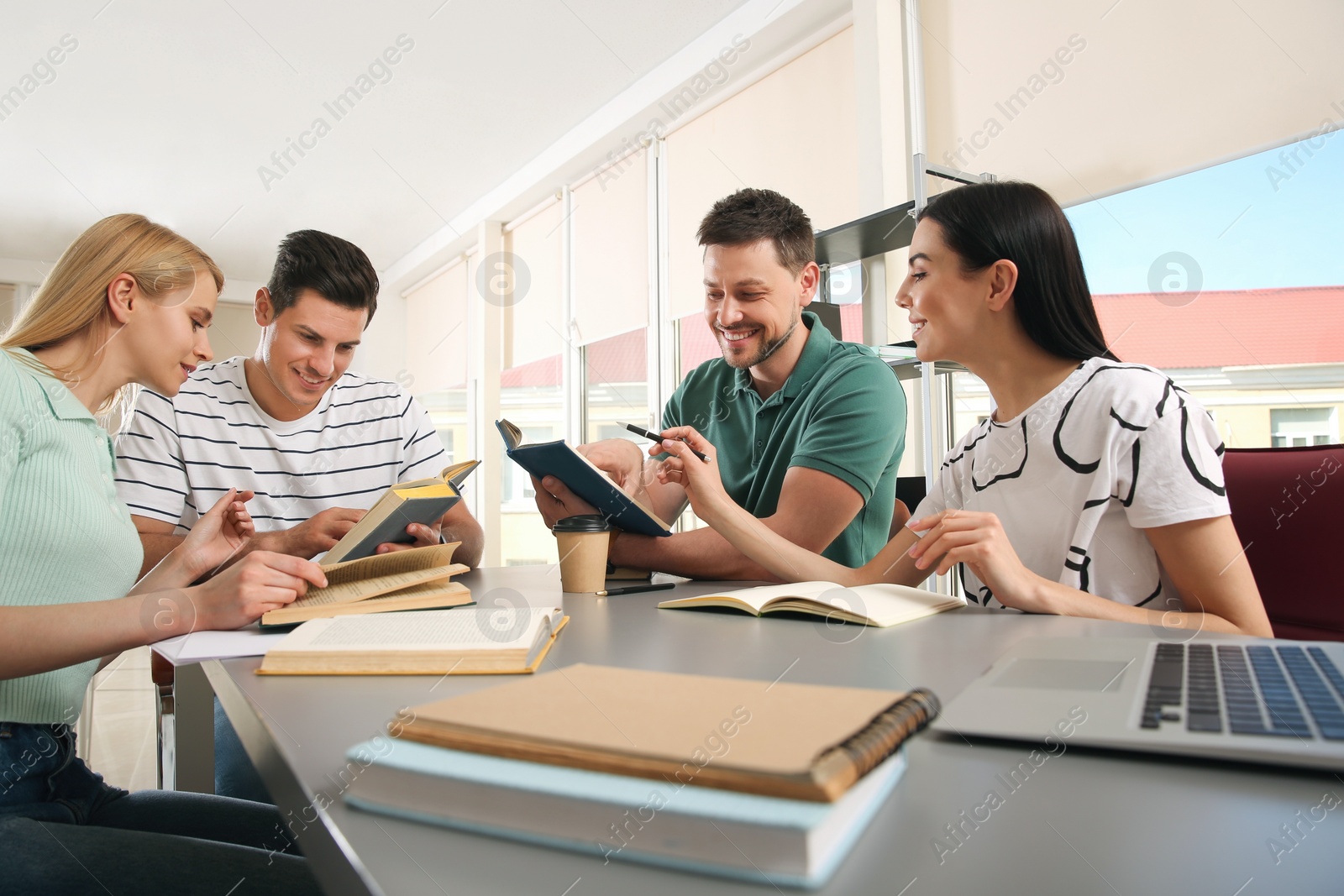 Photo of Young people discussing group project at table in library