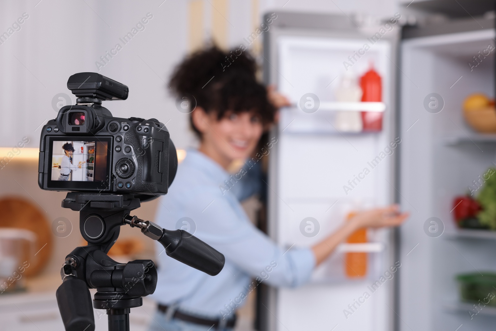 Photo of Food blogger recording video in kitchen, focus on camera