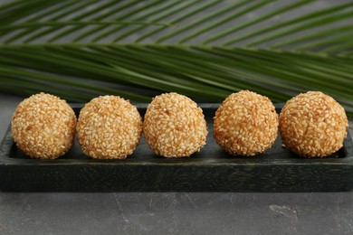 Photo of Delicious sesame balls and green leaf on grey table