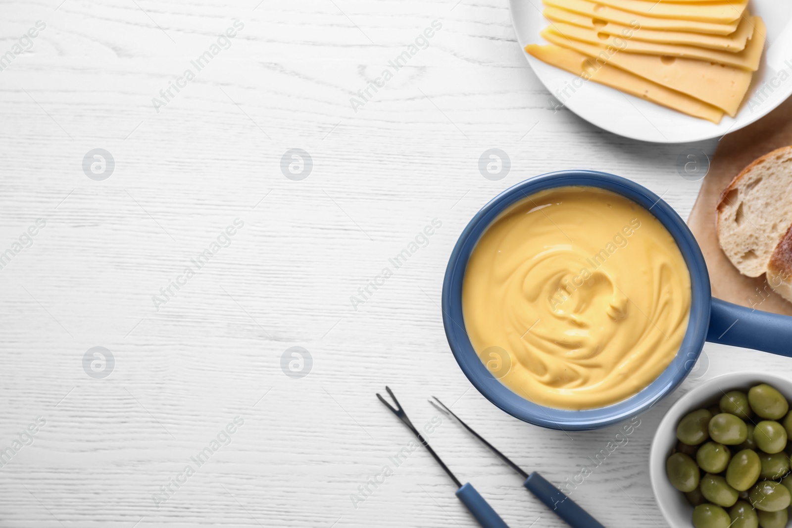 Photo of Flat lay composition with cheese fondue and products on white wooden table, space for text