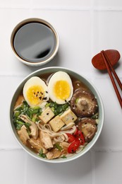 Photo of Noodle soup. Bowl of delicious ramen and chopsticks on white tiled table, top view