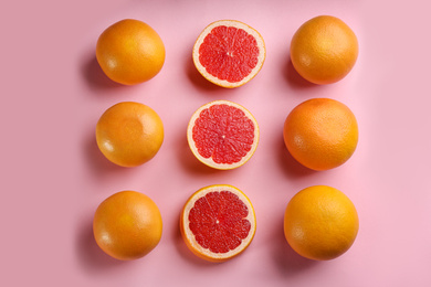 Cut and whole ripe grapefruits on pink background, flat lay