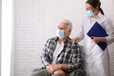 Photo of Doctor taking care of senior woman in protective mask at nursing home. Space for text