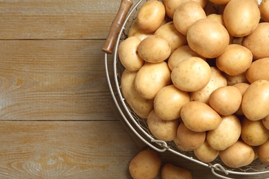 Photo of Raw fresh organic potatoes on wooden background, top view. Space for text