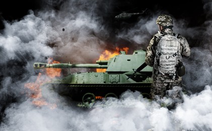 Armed soldier and burning tank in smoke on black background