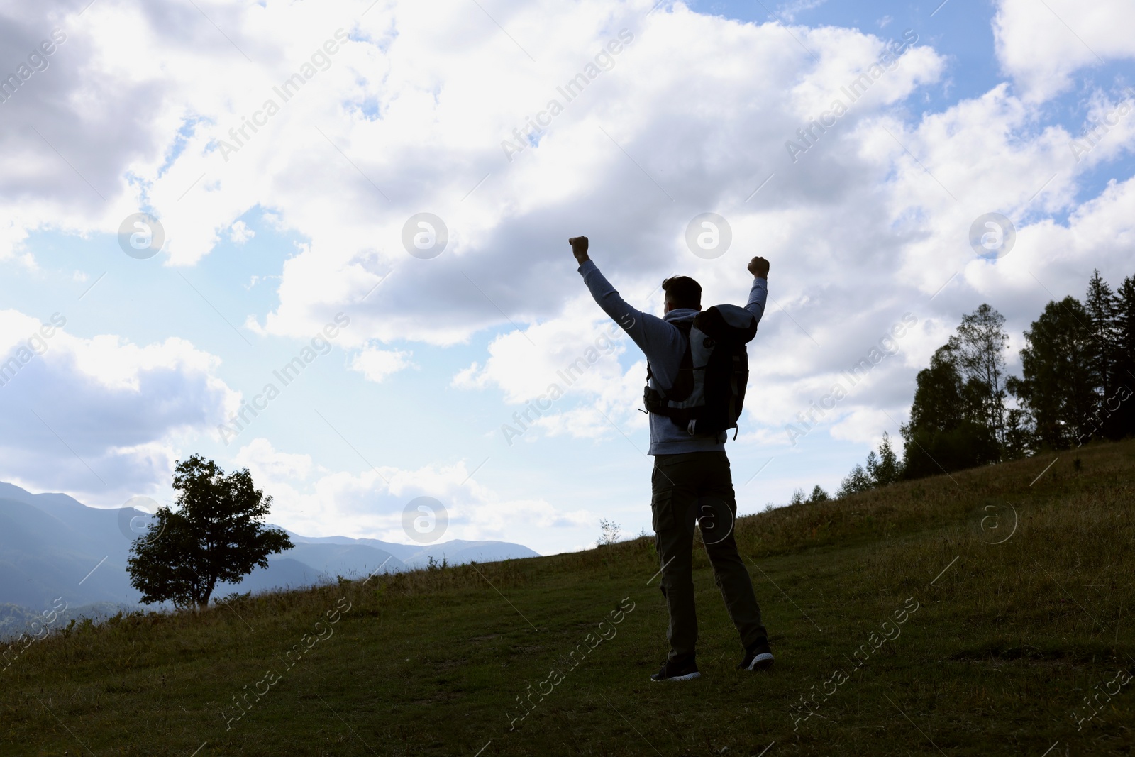 Photo of Triumphant tourist on top of mountain, back view. Space for text