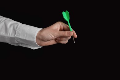 Photo of Businesswoman holding green dart on black background, closeup. Space for text