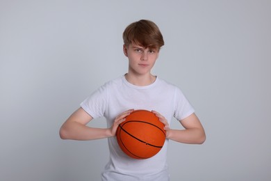 Photo of Teenage boy with basketball ball on light grey background
