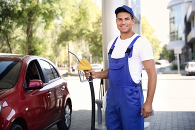 Photo of Worker with fuel pump nozzle at gas station