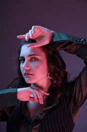 Portrait of beautiful young woman on color background with neon lights