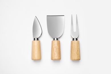 Cheese knives and fork on white background, top view