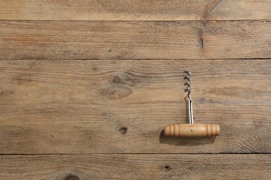 Photo of One corkscrew on wooden table, top view. Space for text