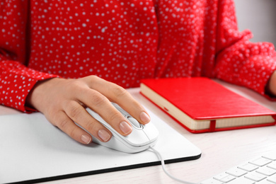 Photo of Woman using modern wired optical mouse at office table, closeup