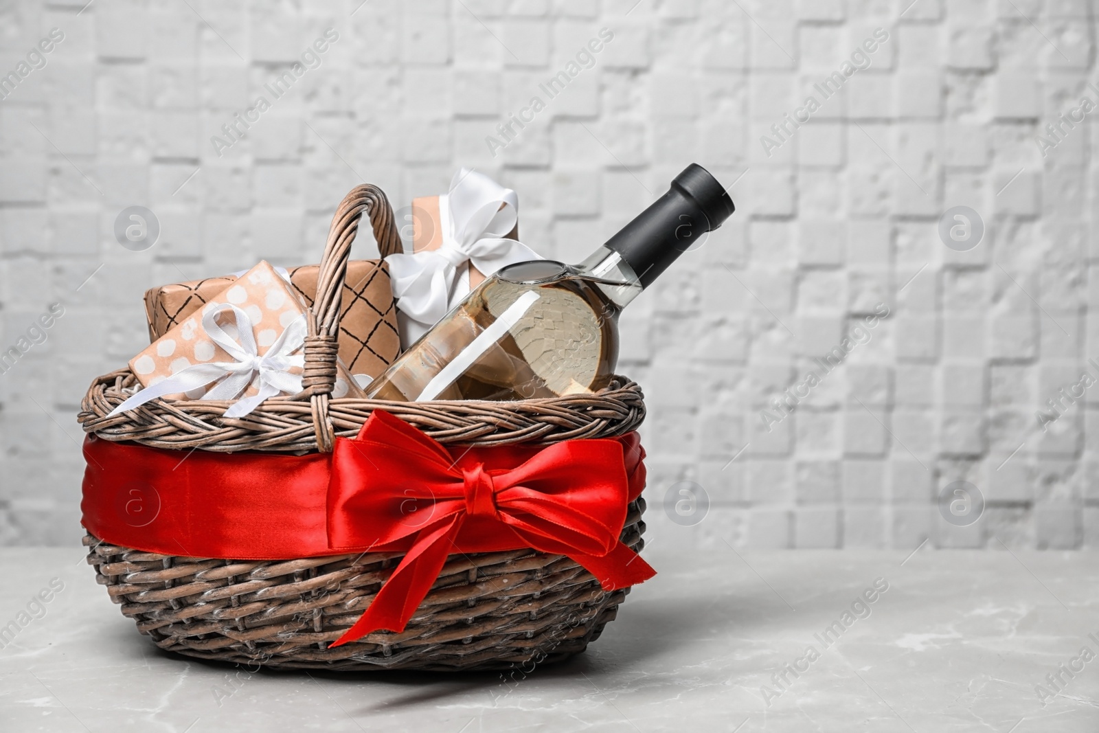 Photo of Gift basket with bottle of wine on light background. Space for text