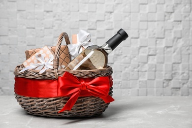 Photo of Gift basket with bottle of wine on light background. Space for text