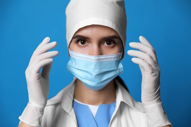 Doctor in protective mask and medical gloves against blue background