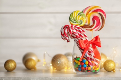 Photo of Different candies in glass jar for Christmas party on table. Space for text