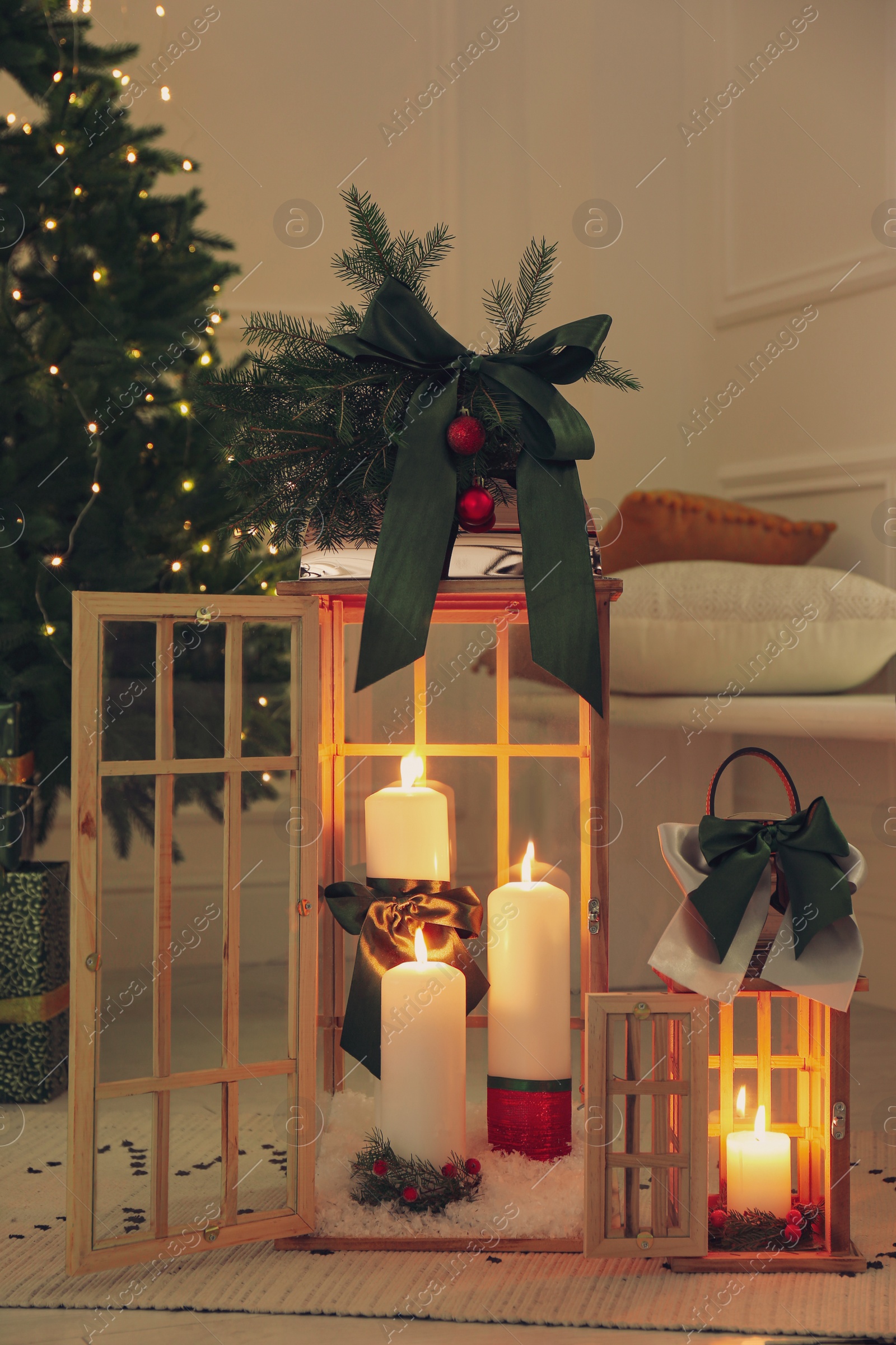 Photo of Wooden decorative lanterns with burning candles near Christmas tree in room