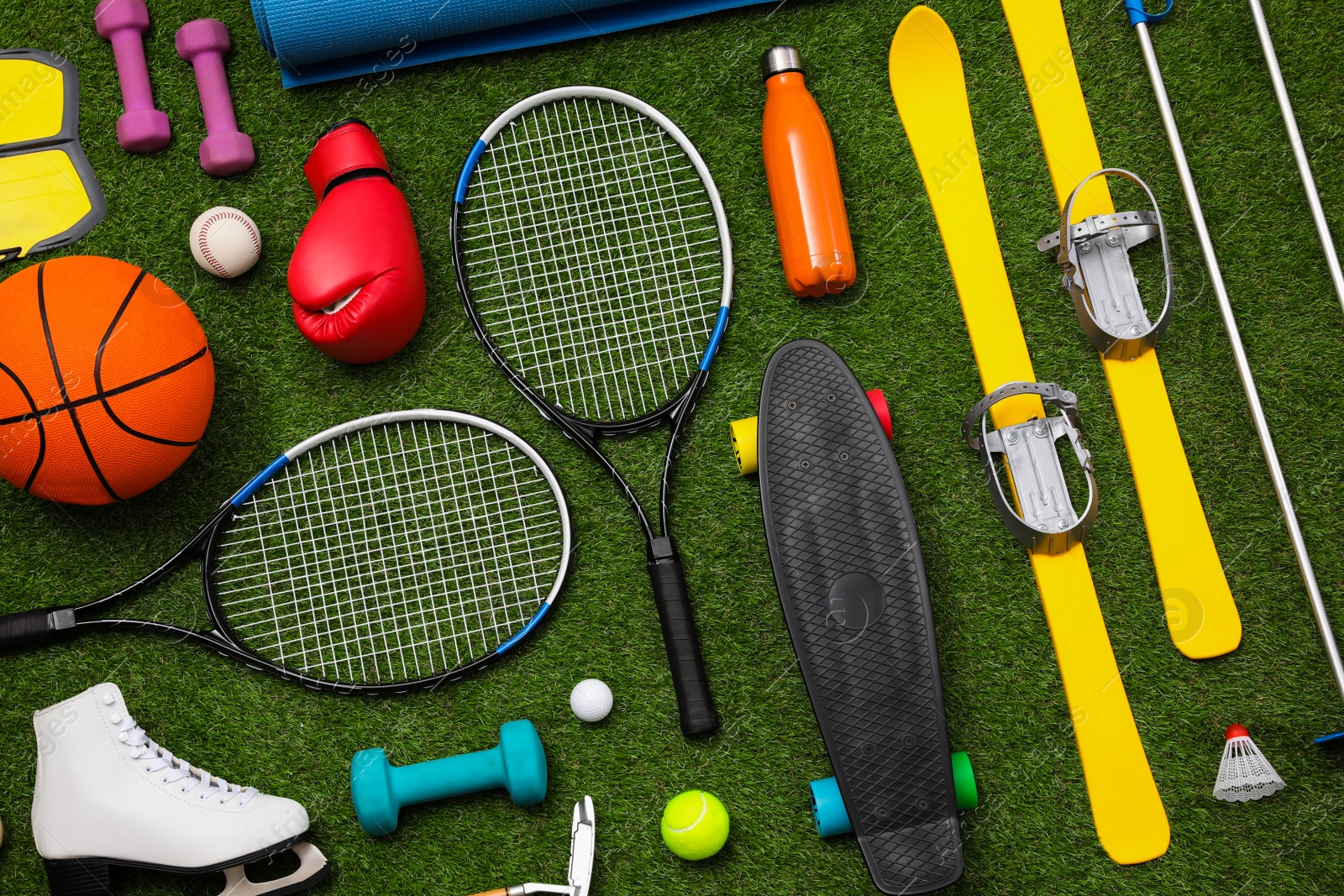 Photo of Different sport equipment on green grass, flat lay