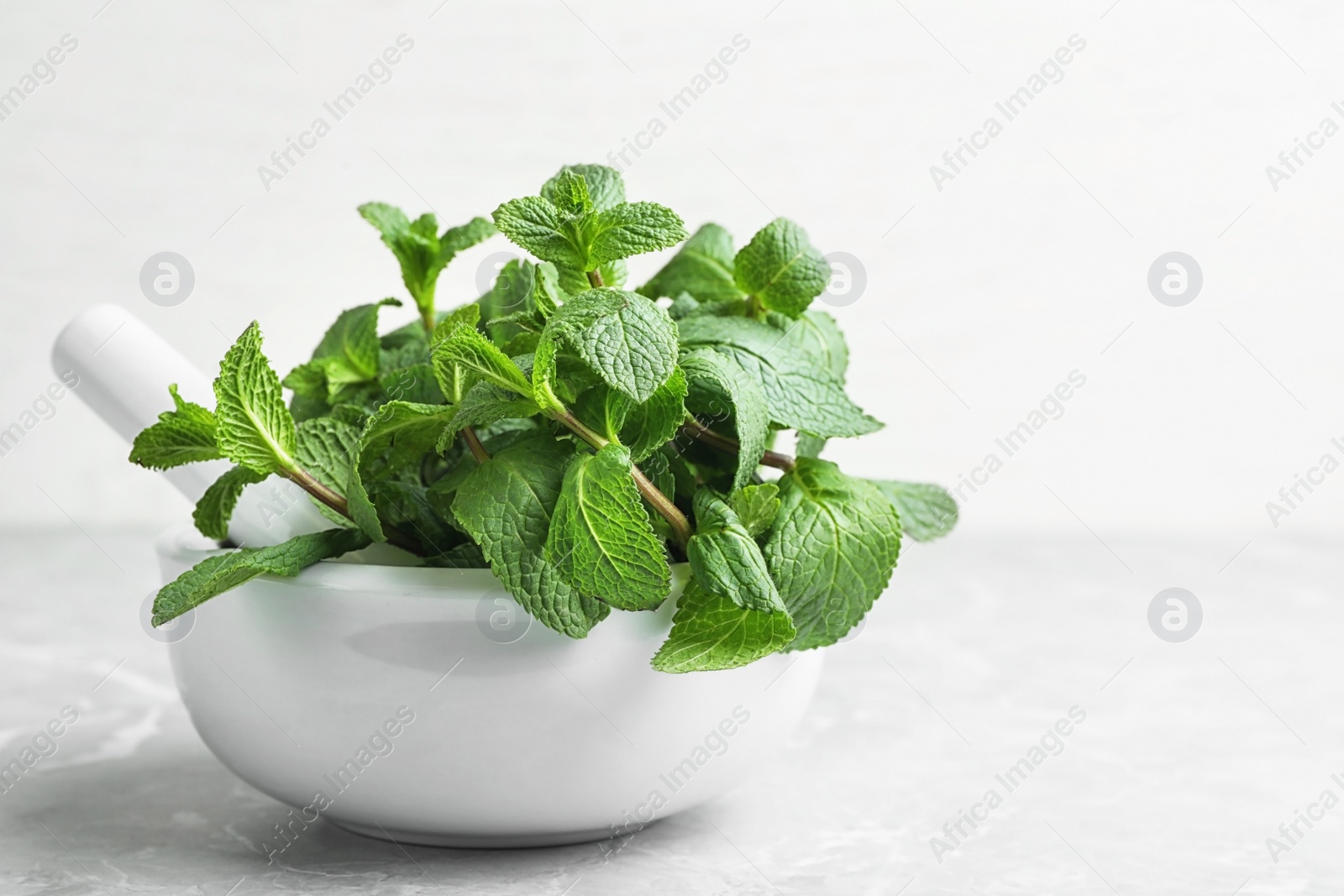 Photo of Mortar with fresh green mint and pestle on table