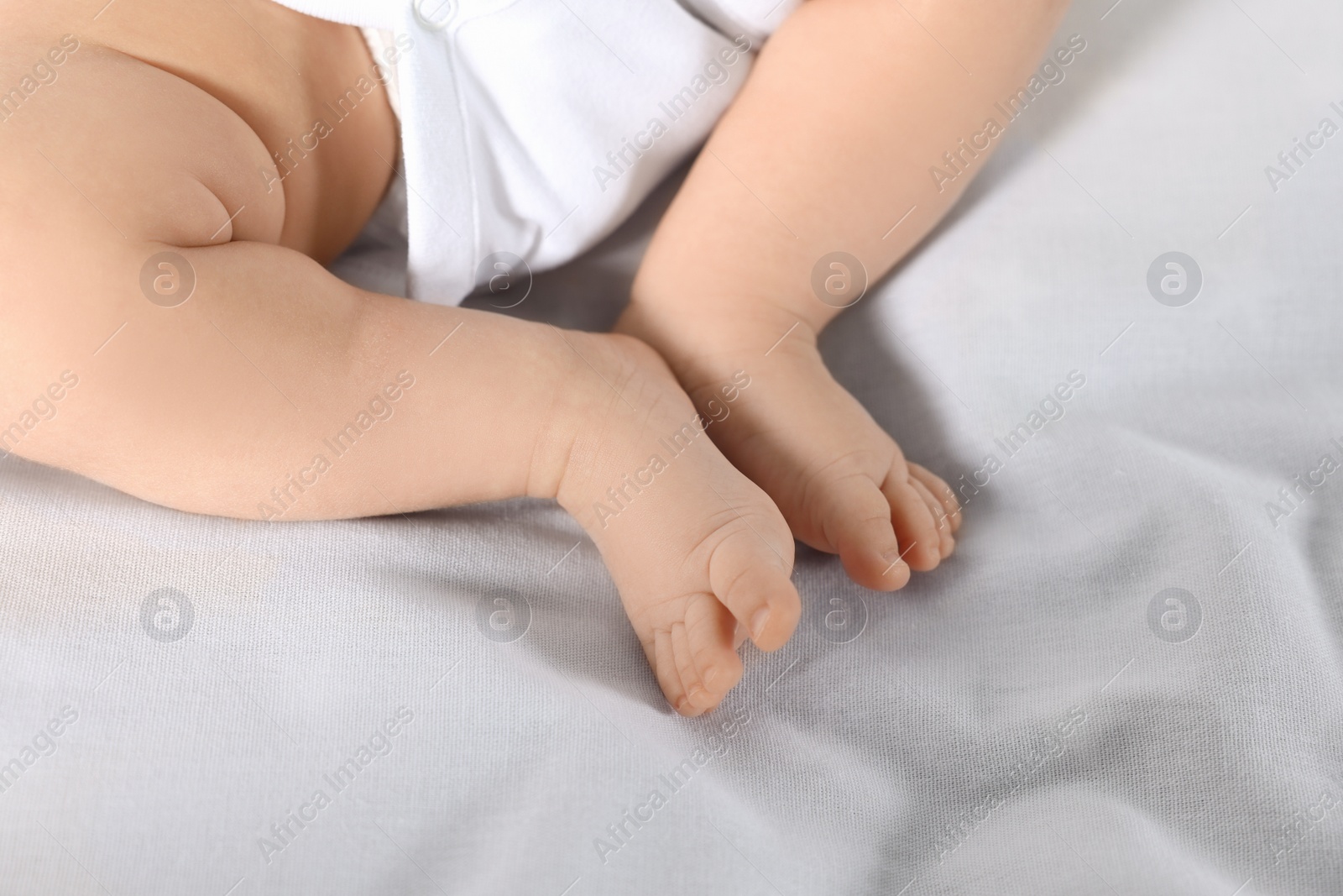 Photo of Little baby in bodysuit on bed, closeup