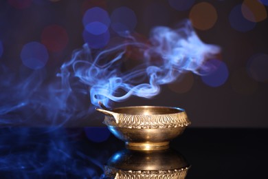 Blown out diya on dark background with blurred lights. Diwali lamp