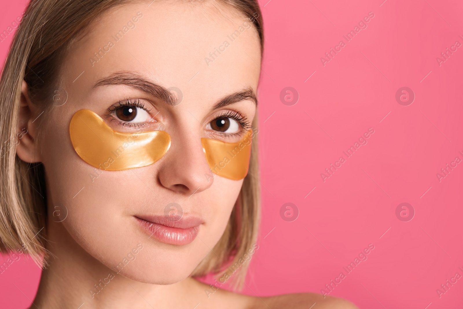 Photo of Beautiful young woman with under eye patches on pink background. Space for text