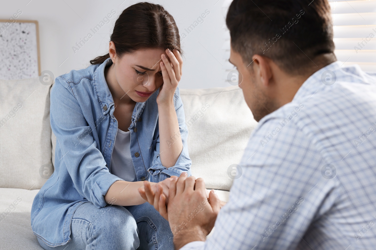 Photo of Unhappy young woman having session with her therapist indoors