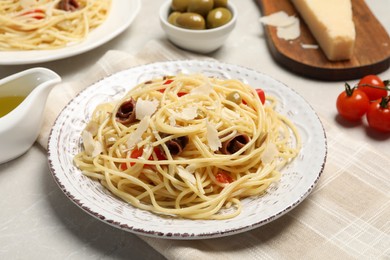 Photo of Delicious pasta with anchovies, tomatoes and parmesan cheese on light grey table