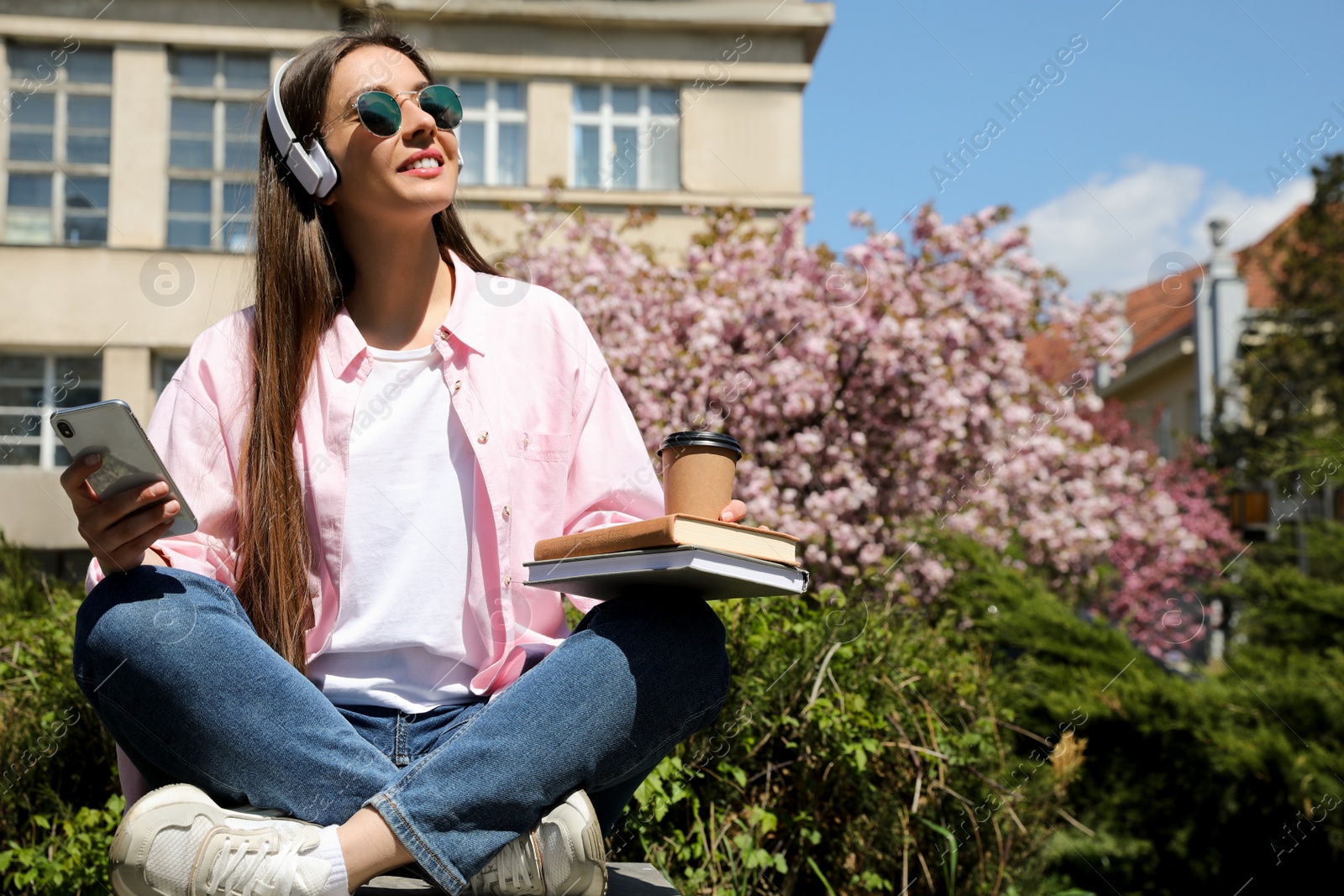 Photo of Young woman listening to audiobook in park