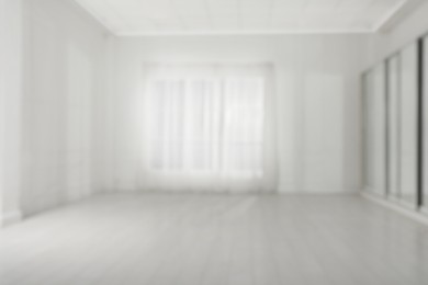 Photo of Empty room with white walls and large window, blurred view