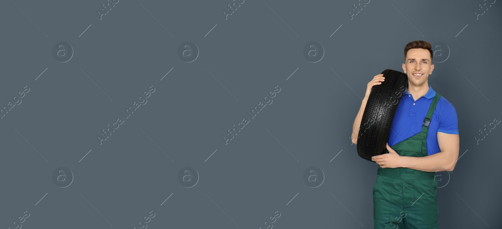 Image of Salesman with car tire on grey background, space for text. Banner design