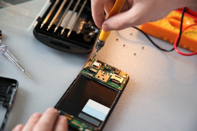 Photo of Technician repairing mobile phone at table, closeup