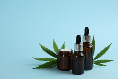 Photo of Cream, hemp leaves, bottles of CBD oil and THC tincture on light blue background. Space for text