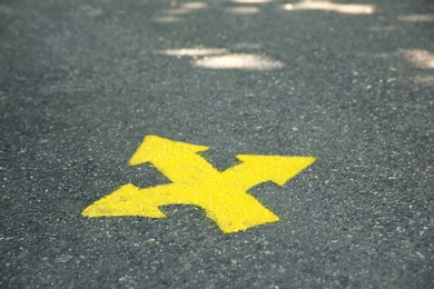 Photo of Bright yellow arrows painted on asphalt road