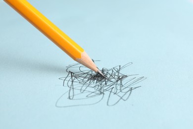 Photo of Drawing scribbles with sharp graphite pencil on light blue background, closeup. Space for text