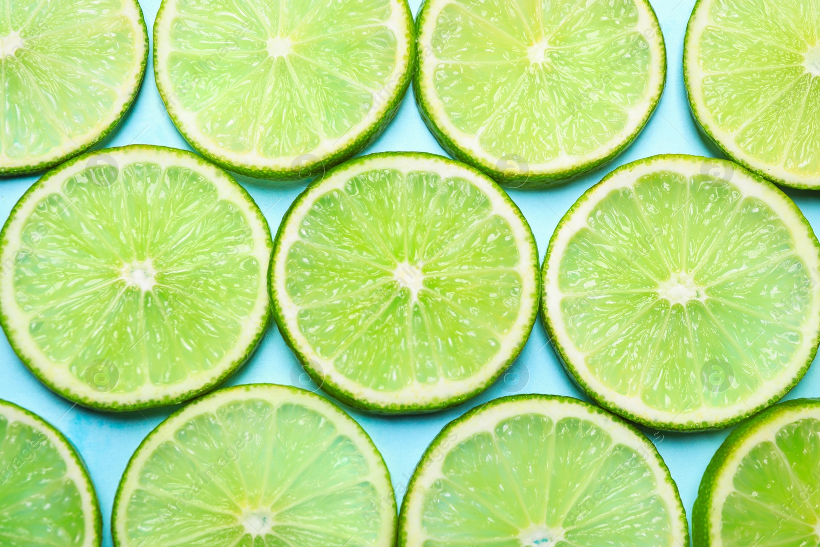 Photo of Juicy fresh lime slices on light blue background, flat lay