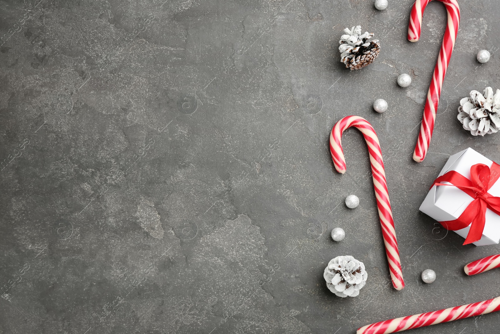 Photo of Flat lay composition with candy canes and Christmas decor on grey table. Space for text