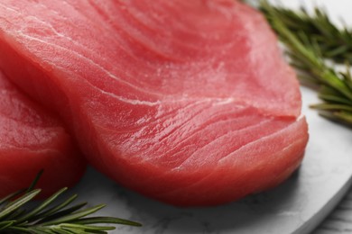 Fresh raw tuna fillets with rosemary on table, closeup