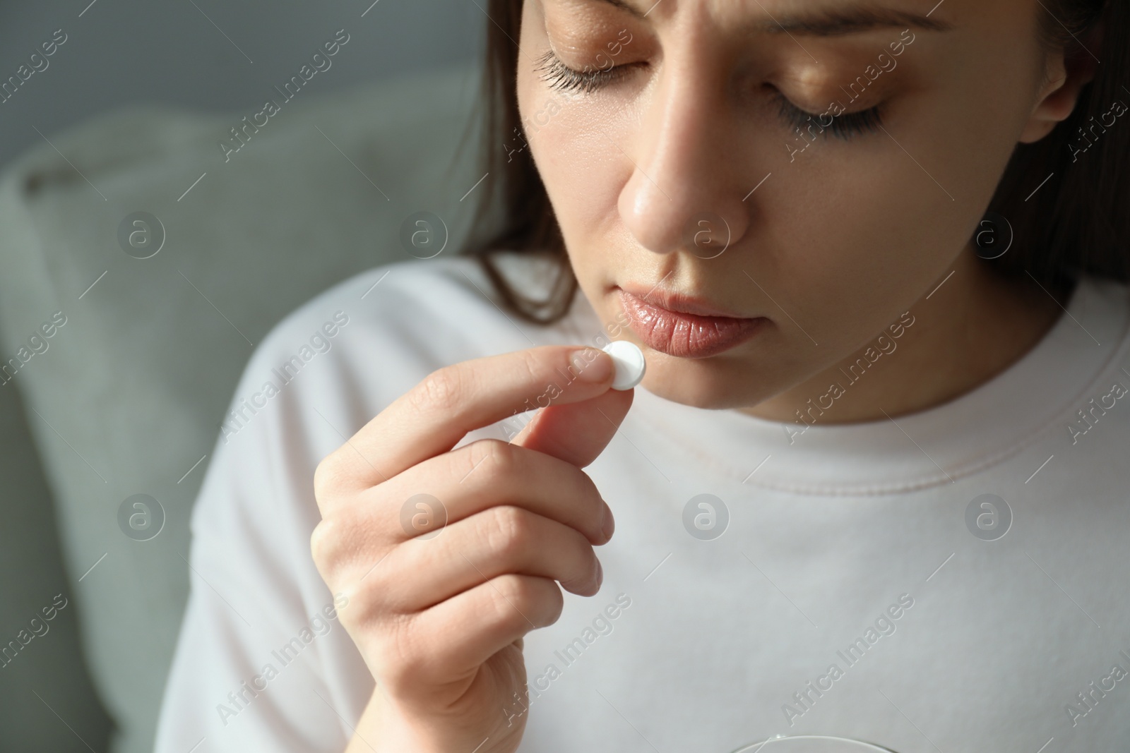 Photo of Young woman taking abortion pill on blurred background, closeup