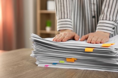 Photo of Woman stacking documents at wooden table indoors, closeup