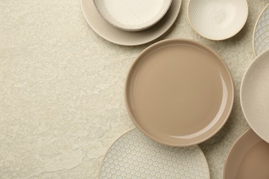Photo of Beautiful ceramic plates and bowls on beige table, flat lay. Space for text