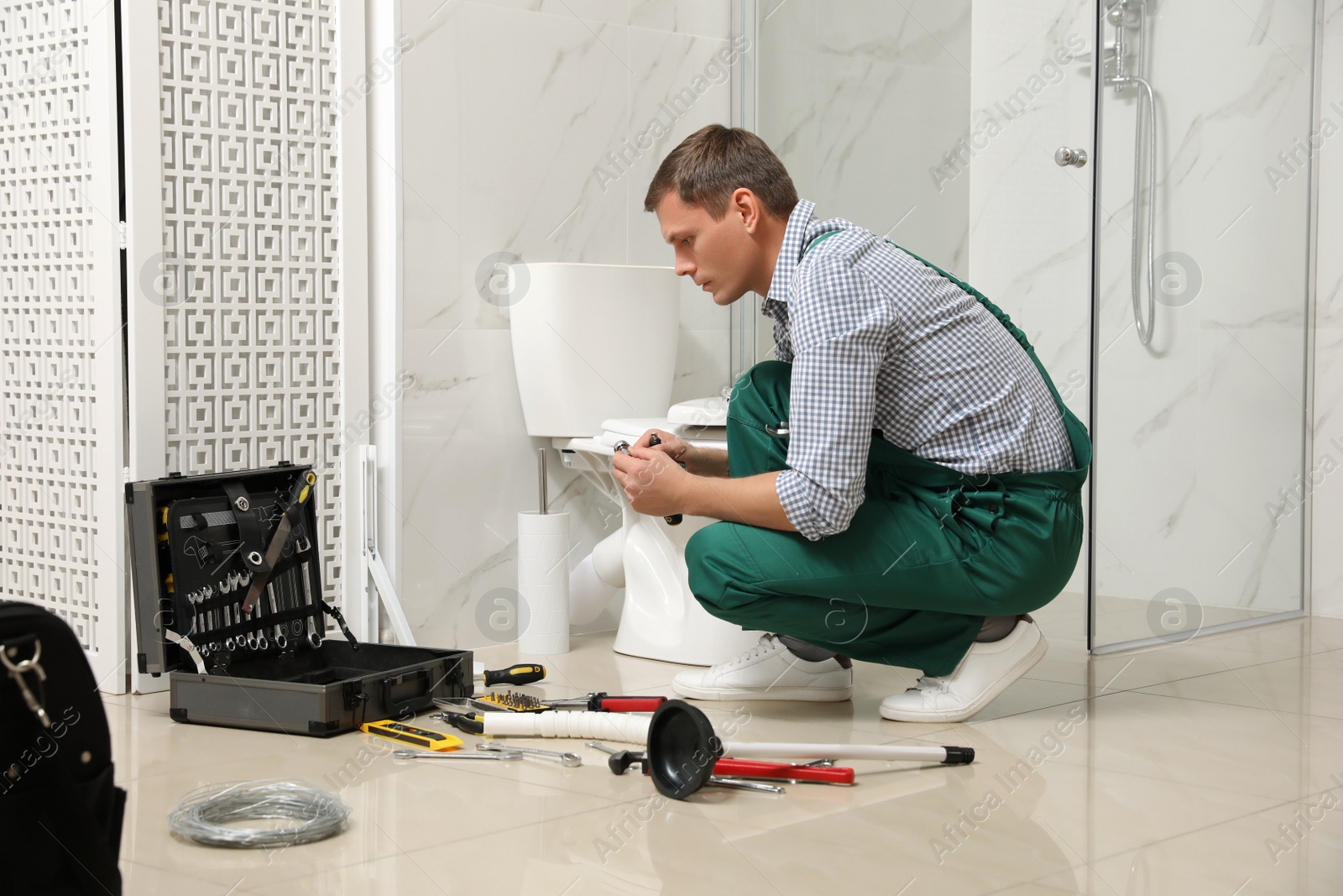 Photo of Professional plumber repairing toilet bowl in bathroom