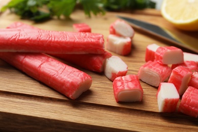 Photo of Delicious crab sticks on wooden board, closeup